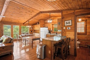 L’intérieur d’un chalet en bois comprend un coin repas, une cuisine et une grande fenêtre.