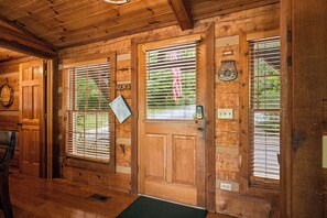 A wooden cabin with a wooden door, two windows with blinds, and a small porch area. - Mountain Views, Hot Tub, Pool Access (Gatlinburg)
