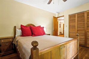 A wooden bed with a headboard, a nightstand, a wardrobe, and a ceiling fan in a room with beige walls. - Mountain Views, Hot Tub, Pool Access (Gatlinburg)