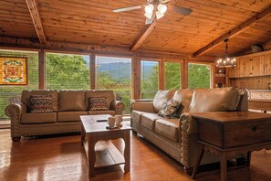Un intérieur en bois avec un canapé, une table en bois et un ventilateur de plafond.