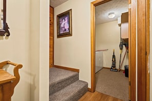 Eine Treppe führt zu einem Raum mit Holzboden, einem gerahmten Bild an der Wand und Putzmitteln im Hintergrund.
