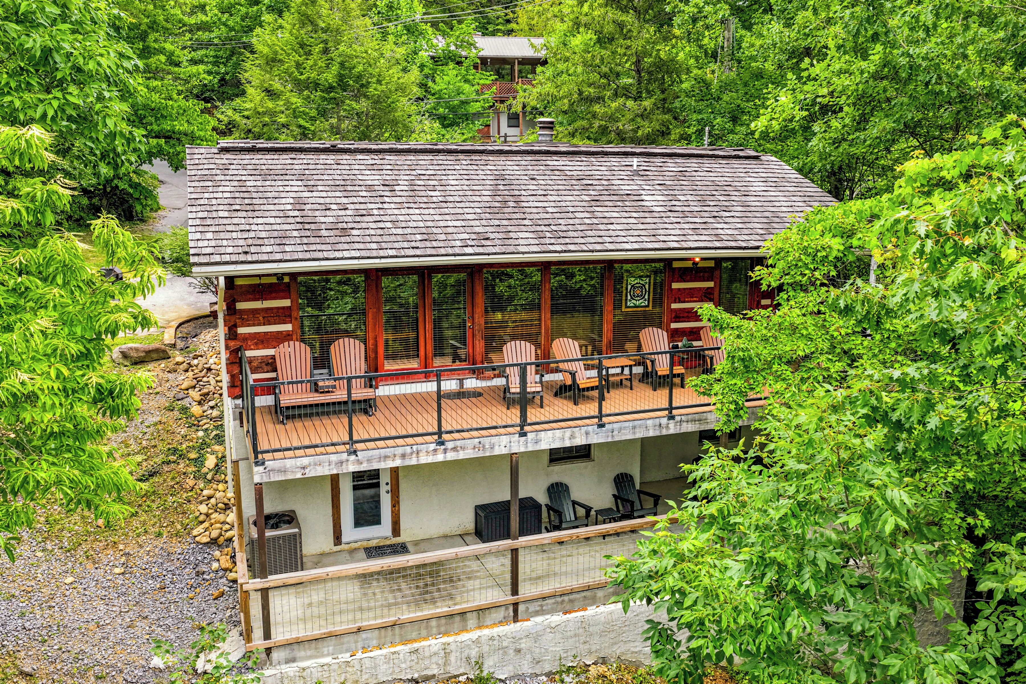 A two-story building with a balcony, outdoor seating, and a view of surrounding greenery.