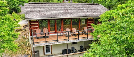 A two-story building with a balcony, outdoor seating, and a view of surrounding greenery.