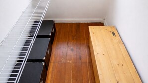 Une petite pièce mansardée avec un plafond en pente, un banc en bois, une étagère en métal et une fenêtre donnant sur un paysage enneigé.