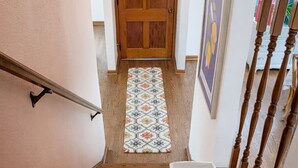 Un escalier en bois avec une rampe, un tapis à motifs et une porte en haut.