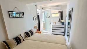Ein Schlafzimmer mit Bett, Kommode, Spiegel und einer Tür, die auf einen Balkon führt.