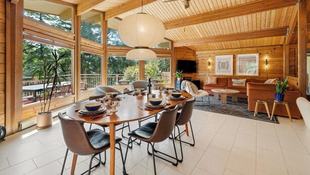A spacious dining area with a wooden table and chairs, large windows, and a ceiling fan. - Lodge style 5 bedroom, 2 kitchens, large deck, outdoor firepit, 1 dog ok (Manzanita)