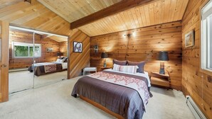 A wooden cabin bedroom with a large bed, two bedside tables, a mirror, and a window. - Lodge style 5 bedroom, 2 kitchens, large deck, outdoor firepit, 1 dog ok (Manzanita)