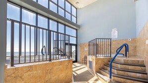 A modern indoor area with a view of the sea, featuring a staircase, metal railings, and tiled flooring. - Phoenix II 2065 by Liquid Life (Orange Beach)