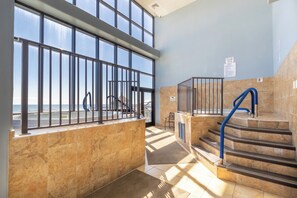 A modern indoor area with a view of the sea, featuring a staircase, metal railings, and tiled flooring. - Phoenix II 2065 by Liquid Life (Orange Beach)