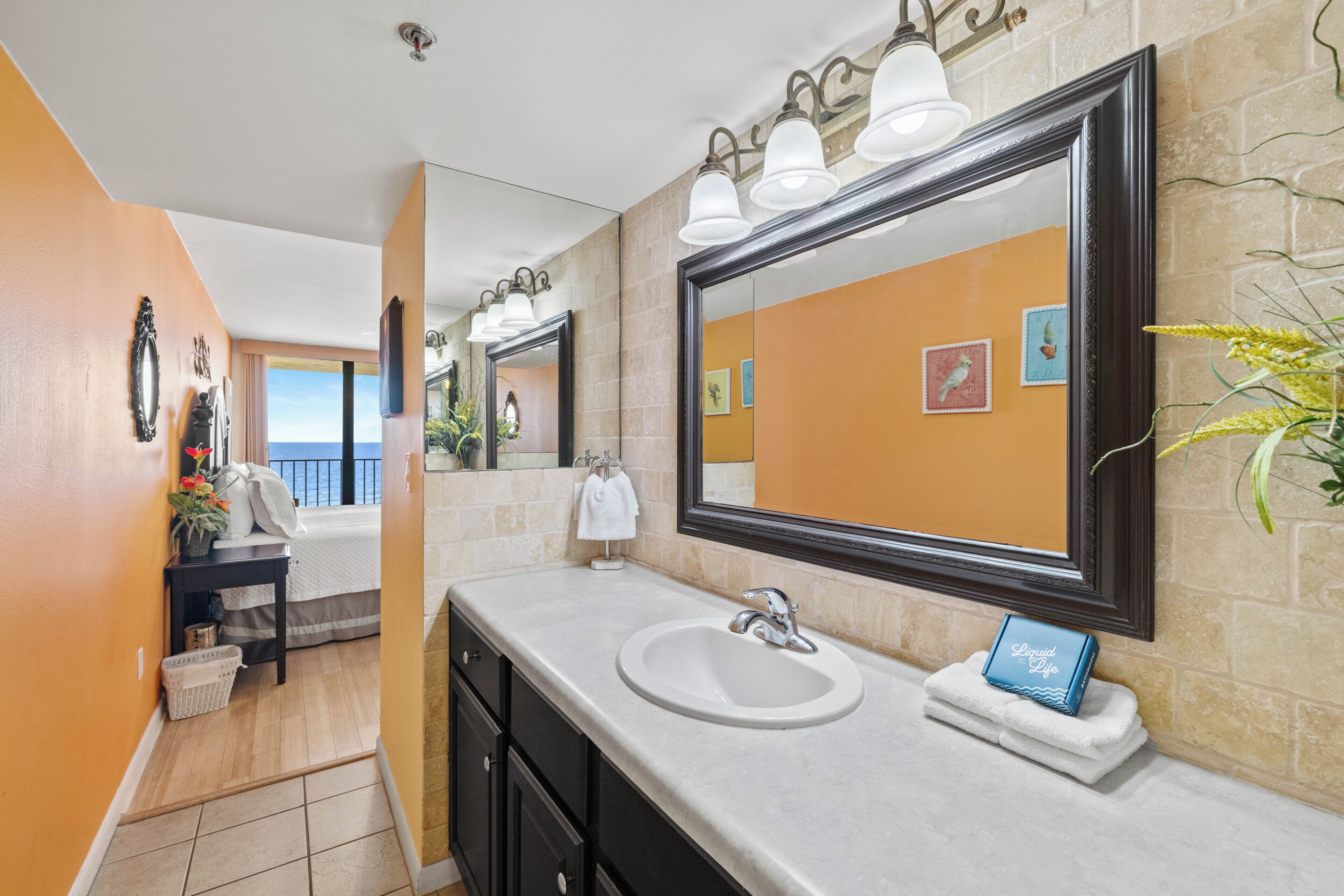 A bathroom with a large mirror, a sink, and a towel rack.