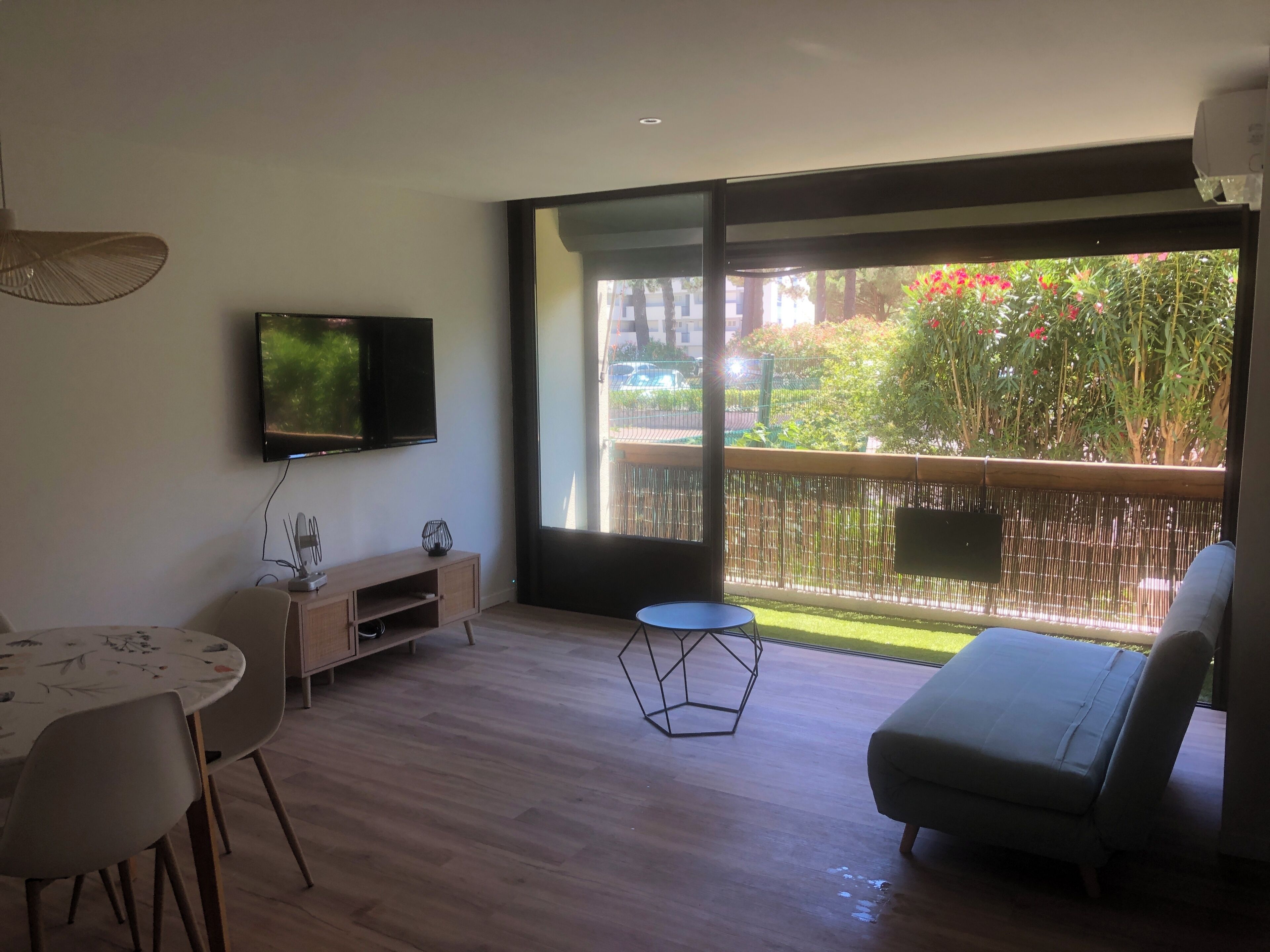 Ein modernes Wohnzimmer mit Flachbildfernseher, einem Esstisch mit Stühlen, einer Couch und einem kleinen runden Tisch.