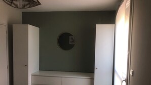 Une pièce avec un banc intégré, un miroir rond et une porte.