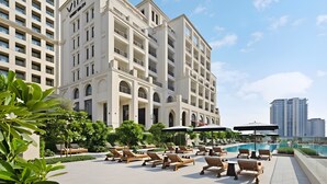 Ein Hotel mit Poolbereich, Außenbereich zum Sitzen und einem großen Gebäude mit Balkonen.