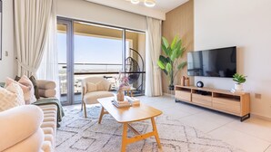 Ein modernes Wohnzimmer mit Sofa, Couchtisch, Fernseher und einem Balkon mit Blick.