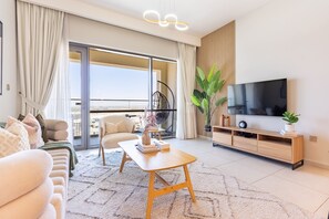 Een moderne woonkamer met een bank, salontafel, televisie en een balkon met uitzicht.