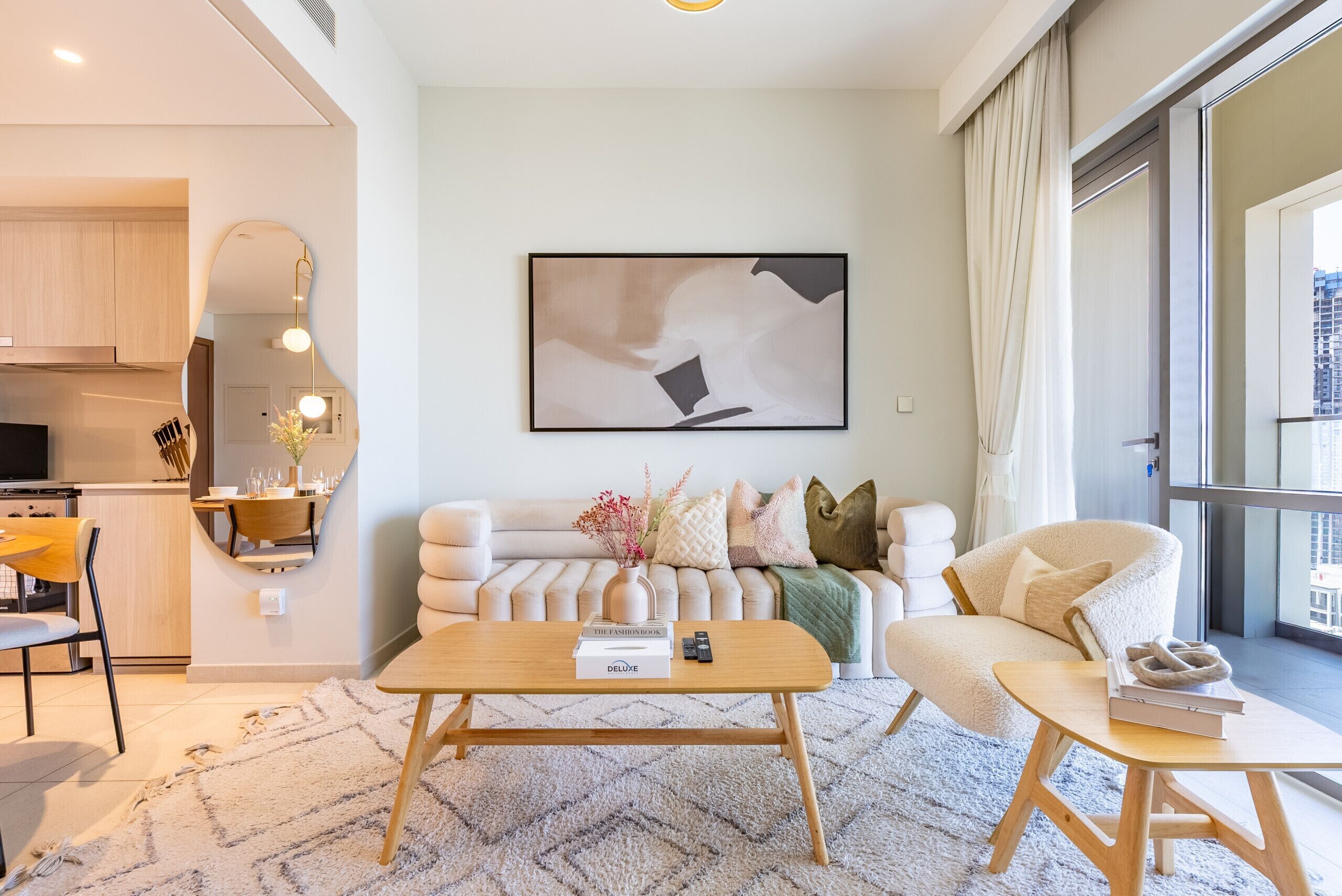 Een moderne woonkamer met een bank, salontafel en een eethoek, met een keuken op de achtergrond.