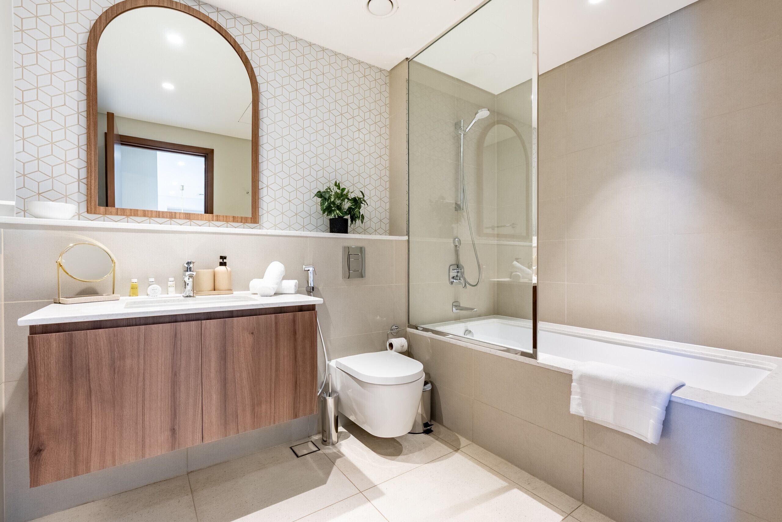 A modern bathroom with a wooden vanity, a glass shower enclosure, and a large mirror.
