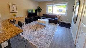 Ein Wohnzimmer mit einer Couch, einem Couchtisch, einem Fernseher und einem Essbereich mit Stühlen und einem Tisch.