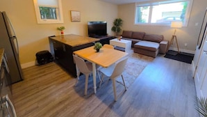 Ein gemütlicher Wohnbereich mit Küchenzeile, Essbereich, Sofa und Fernseher.