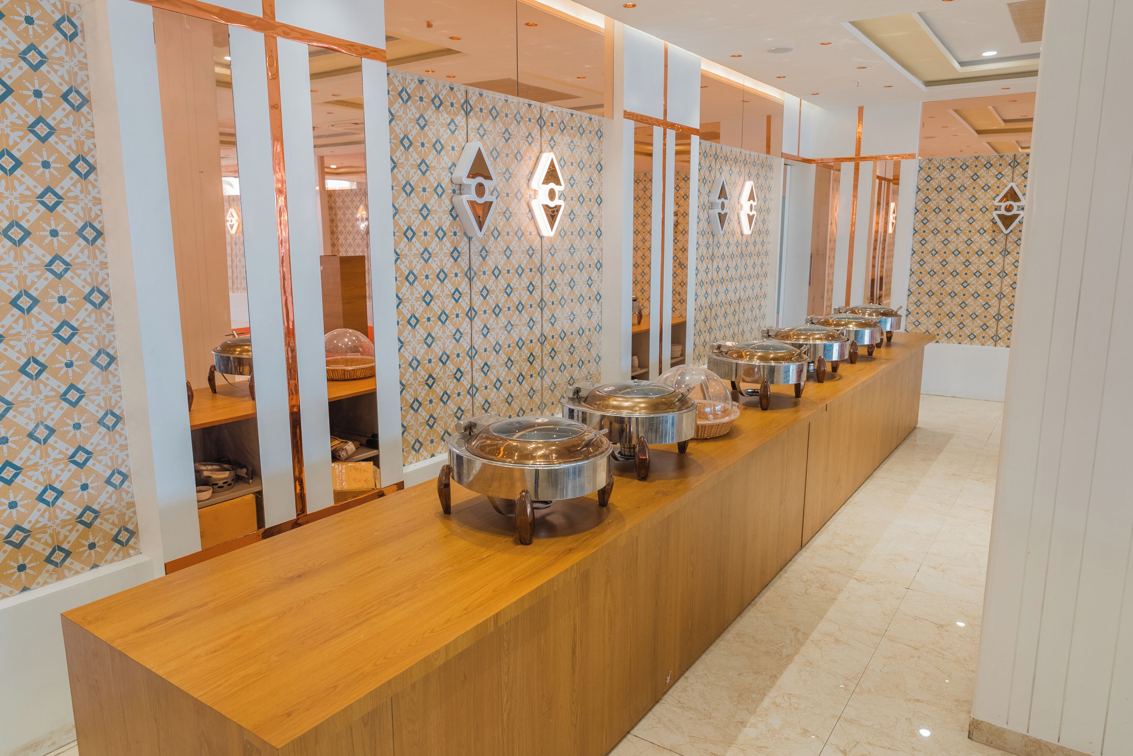 Un'attrezzatura per buffet con diverse postazioni di servizio, un bancone in legno e decorazioni murali a motivi decorativi.