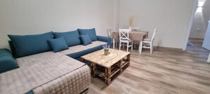 Een woonkamer met een bank, een salontafel en een eetgedeelte met stoelen en een tafel.