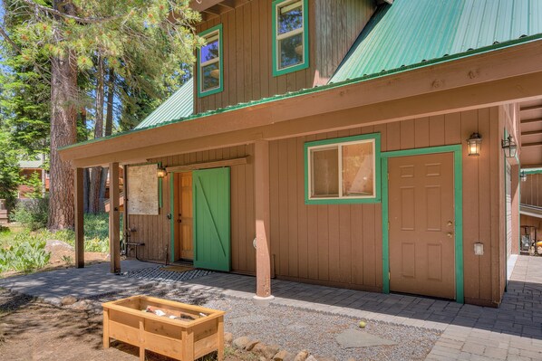A wooden cabin with a green door, a window, and a porch area. - Walnut Woods: Studio, 1 BA Apartment in Homewood, Sleeps 2 (Homewood)
