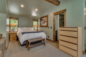 Ein Schlafzimmer mit einem Bett, Nachttischen, einer Holzbank, einem Schminktisch und einer Tür zu einem Badezimmer.