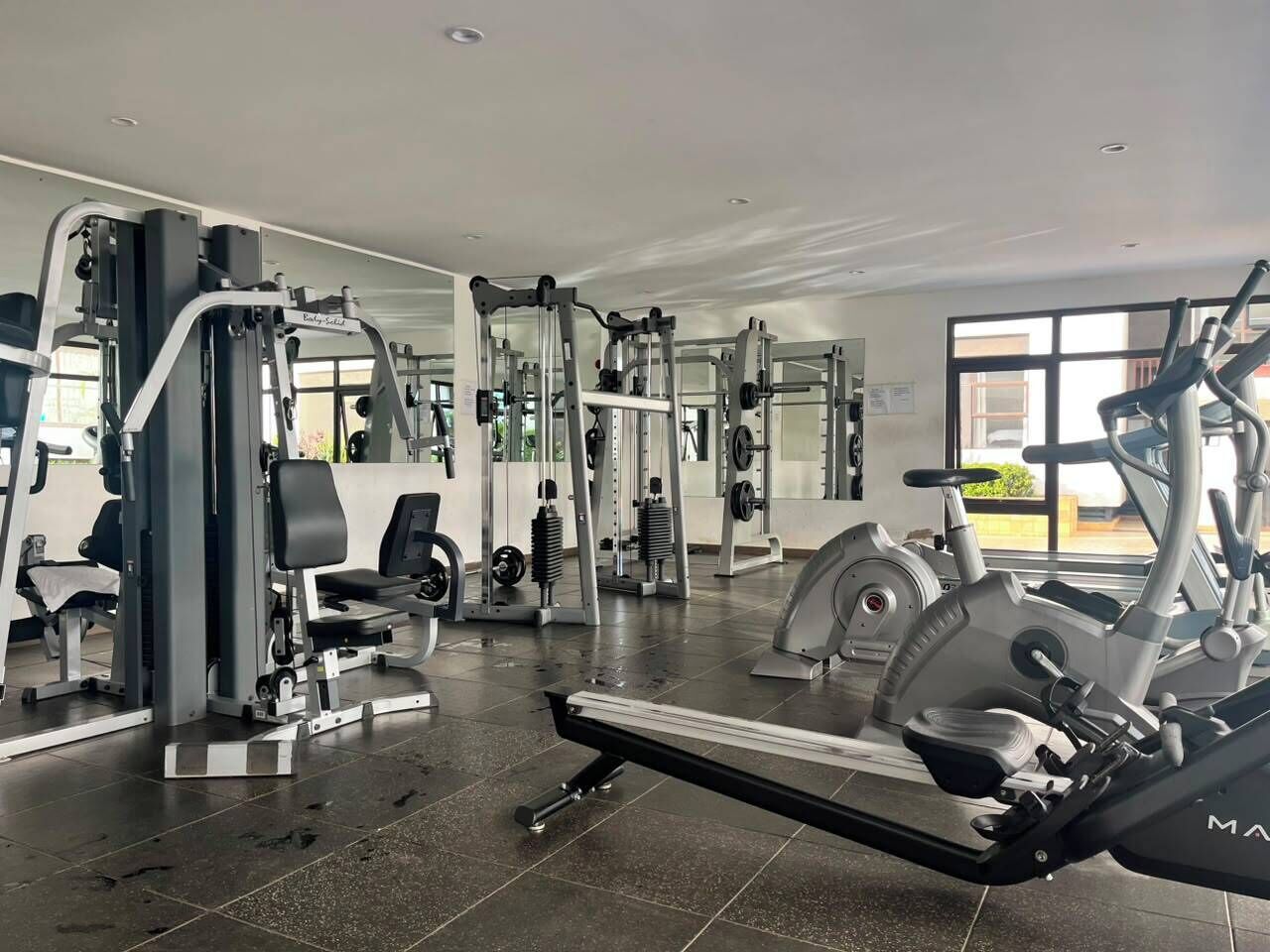 Une salle de sport équipée de divers appareils d’exercice, notamment des tapis de course et des appareils de musculation.