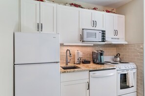 A modern kitchen with white cabinets, a built-in microwave, a stainless steel kettle, and a stove. - Basecamp to All Things Northern Michigan (Boyne Falls)