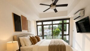 Ett sovrum med en säng, en takfläkt, en tv och ett stort fönster.