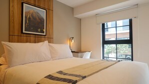 Habitació d'hotel amb un llit gran, un quadre a la paret, una làmpada de nit i una finestra amb vistes.