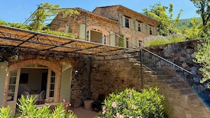 A stone building with a covered patio, outdoor seating, and a stone staircase.
