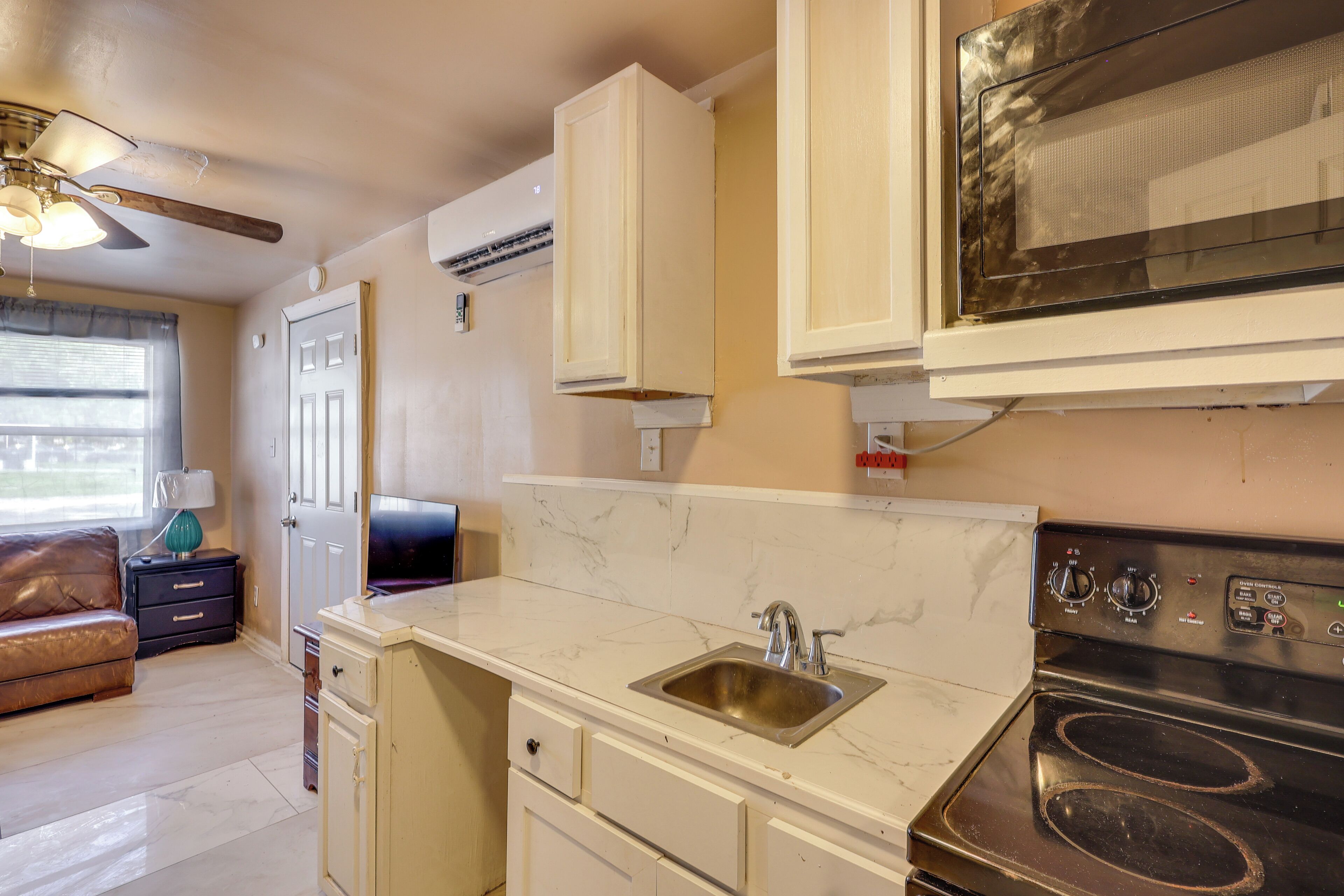 A kitchen with a sink, stove, cabinets, and a ceiling fan.