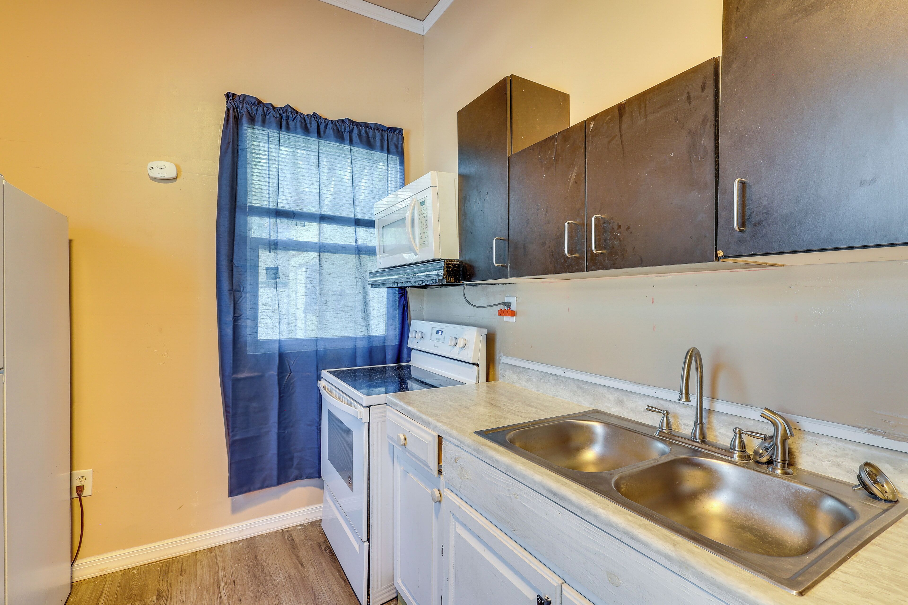 A compact kitchen with a microwave, stove, sink, and cabinets.