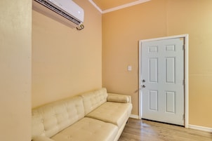 Un sofá color beige, una puerta blanca y un equipo de aire acondicionado instalado en la pared.