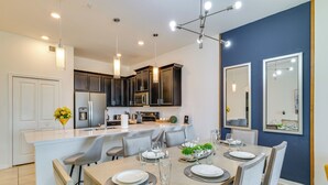 A modern kitchen with dark cabinets, a central island, and pendant lighting. - 9 Mi to Disney Championsgate Condo Plus Water Park (Davenport)
