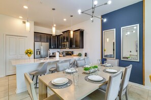 A modern kitchen with dark cabinets, a central island, and pendant lighting. - 9 Mi to Disney Championsgate Condo Plus Water Park (Davenport)