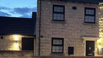 A stone building with a dark roof, multiple windows, and a door.