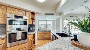 A modern kitchen with wooden cabinets, a Bosch oven, granite countertops, and a large window offering a view. - Golf Course Retreat: Pool, Rv/boat Pkg, Lake Views (Lake Havasu City)