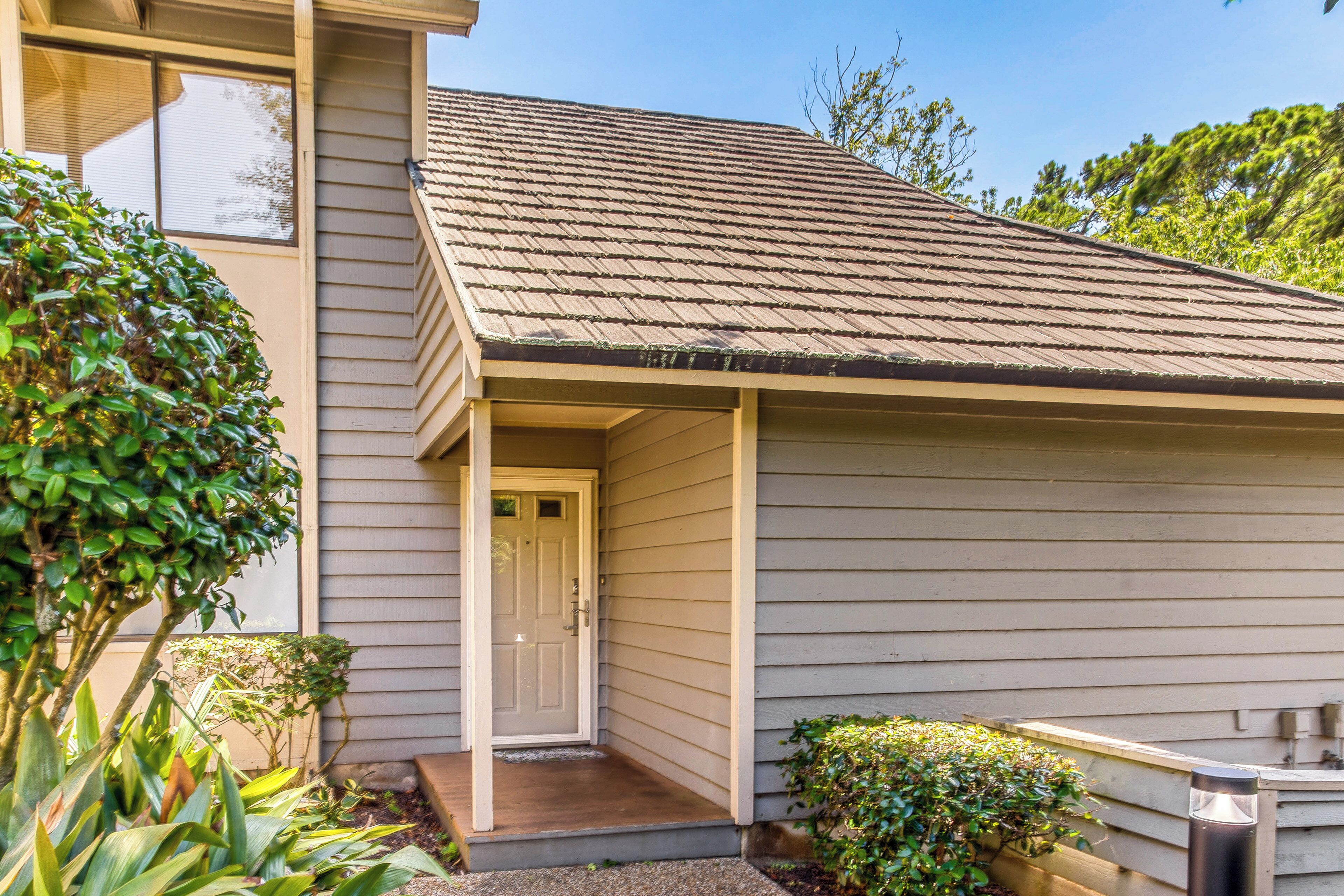 A house with a front porch, a door, and a small garden area with plants.