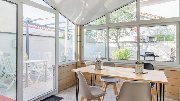 A conservatory with a dining table, chairs, and a view of the outside. - A 5-minute walk from downtown, a charming house in a quiet, secluded location. (La Teste-de-Buch)