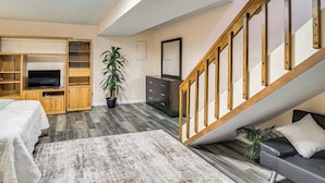 A living room with a TV, wooden entertainment unit, staircase, and a sofa. - 3 Mi to Old Town Arvada! Family Townhome w/ Patio (Arvada)