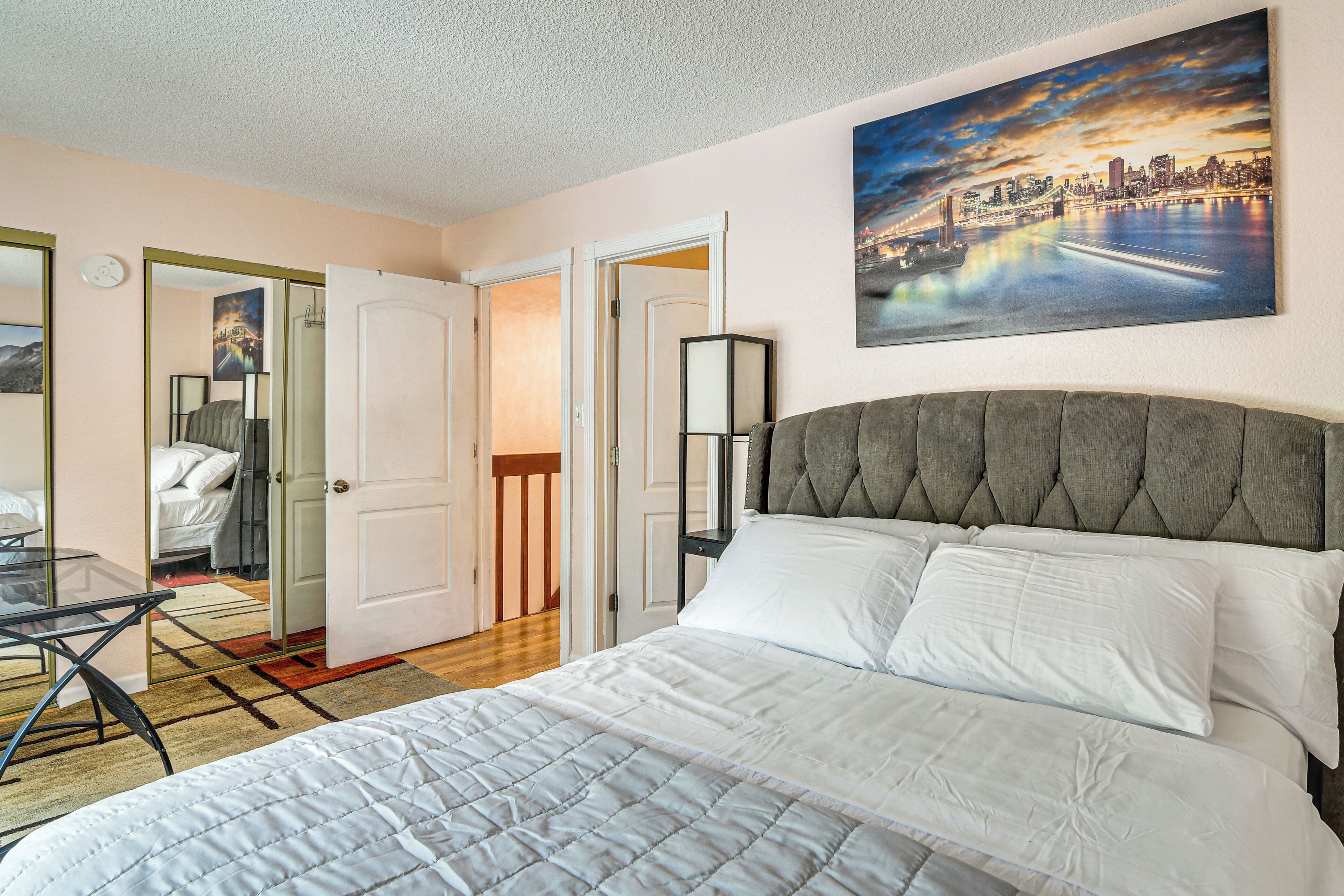 Una habitación de hotel con una cama, un cuadro de un paisaje urbano, una silla y un escritorio.