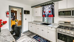 A modern kitchen with white cabinets, a stainless steel stove, and a microwave.