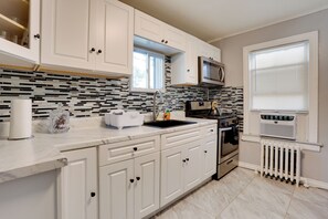 A modern kitchen with white cabinets, a black and white backsplash, a stainless steel sink, and a built-in microwave. - 8 Mi to Metlife Stadium! Teaneck Retreat w/ Yard (Teaneck)