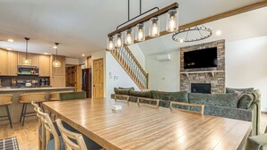 A modern kitchen with wooden cabinets, a dining table with chairs, a staircase, and a living area with a sofa and fireplace. - 1 Mi to Beach! Home w/ Game Room in Albrightsville (Albrightsville)