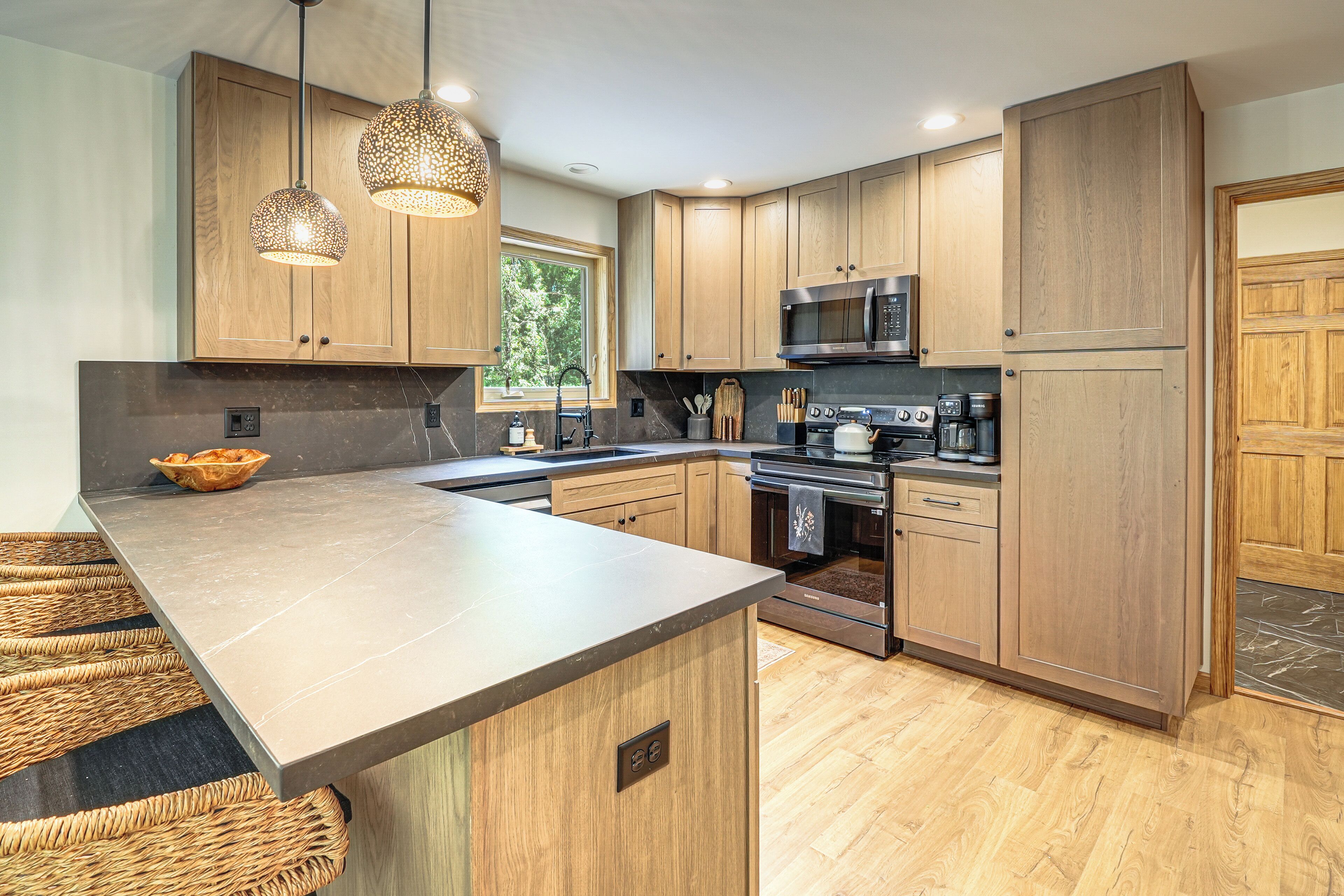 A modern kitchen with wooden cabinets, stainless steel appliances, and a large island with a woven bench.