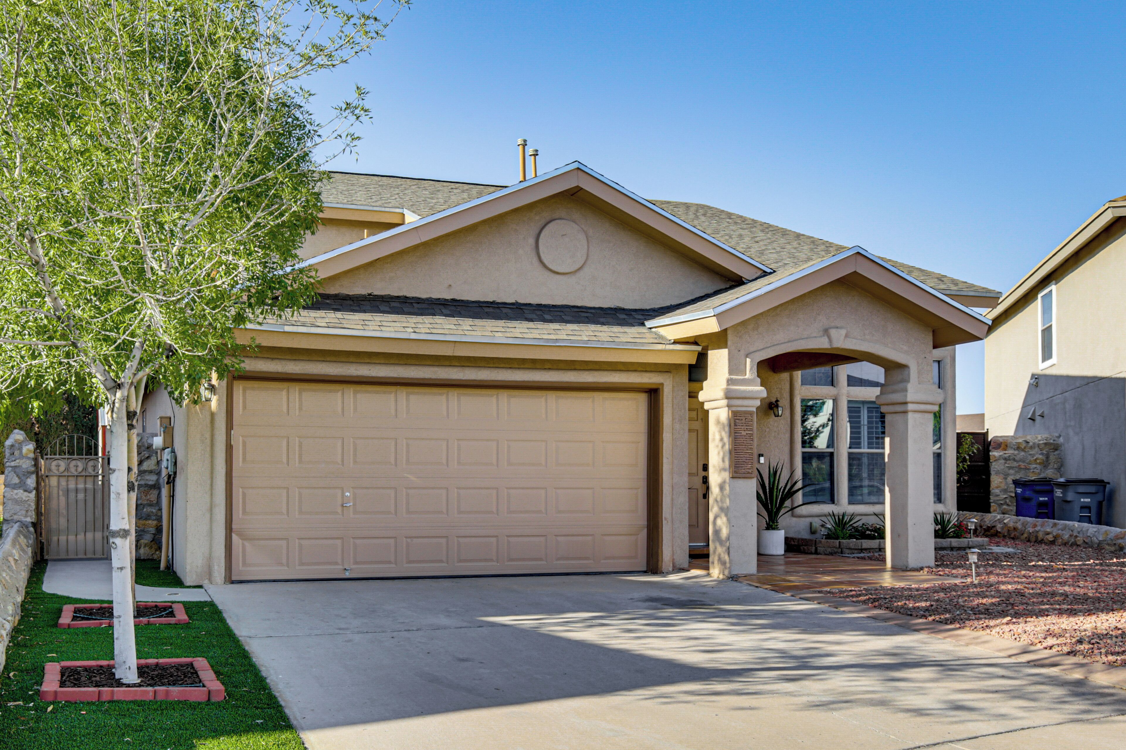 A residential house with a garage, a driveway, and a well-maintained lawn.