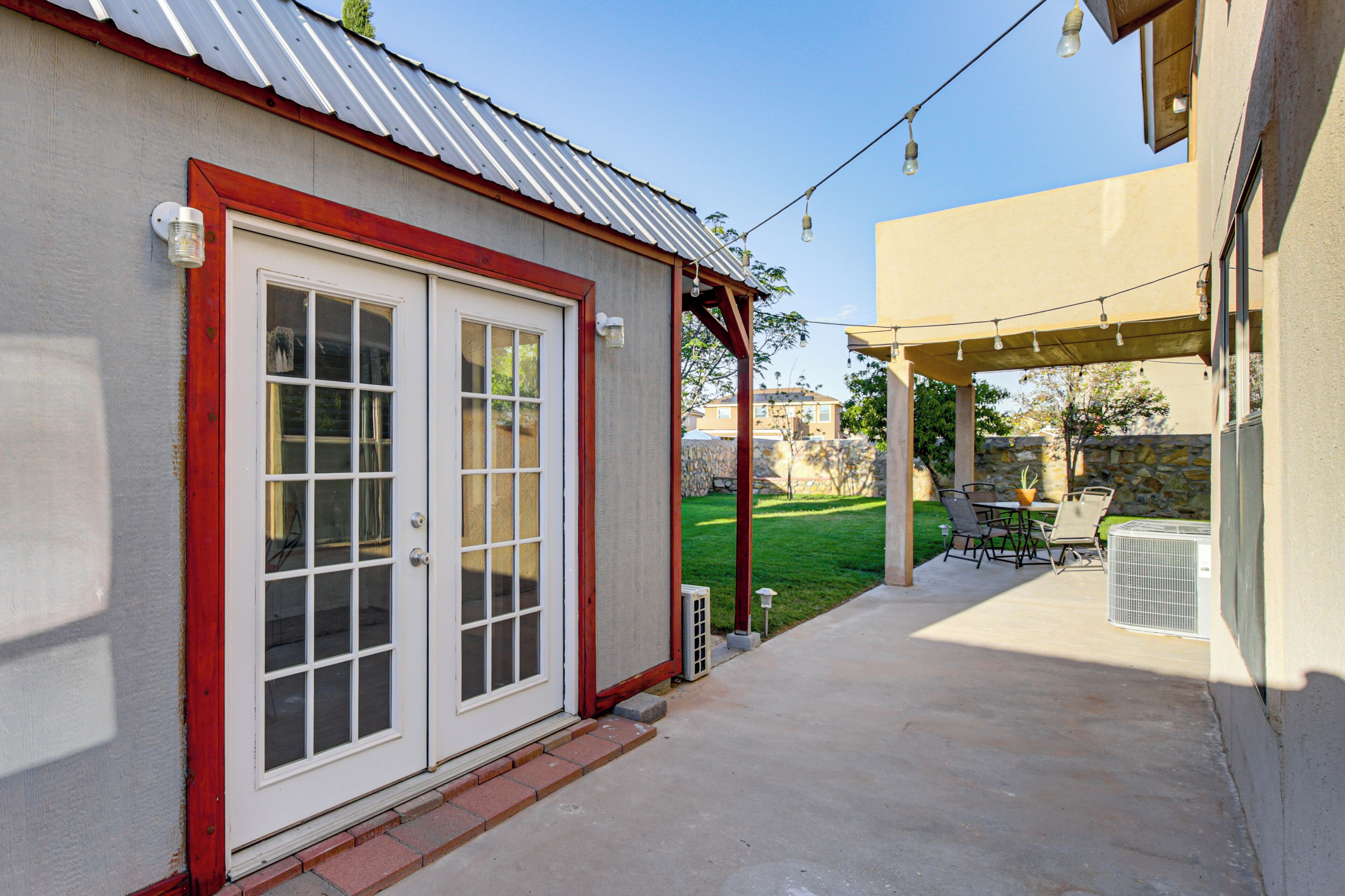 A patio area with a covered seating area, a white door with glass panels, and a stone wall in the background.